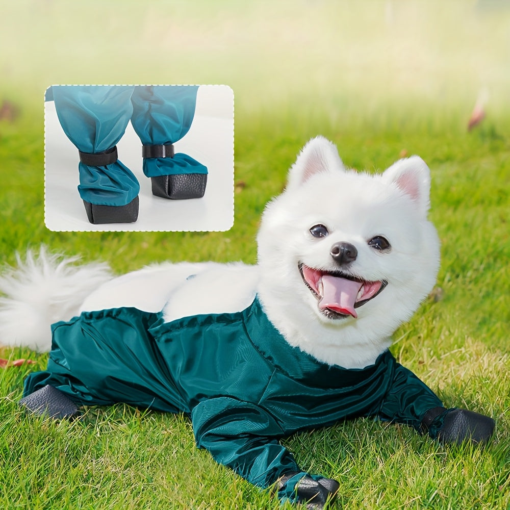 White dog wearing a green raincoat with black boots on grass